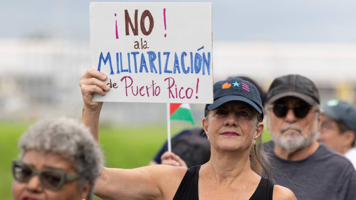 A demonstrator holds a sign that reads in Spanish, "No to the militarization of Puerto Rico" during a protest outside the Muñiz Air National Guard Base in Carolina, Puerto Rico, Sunday, Sept. 7, 2025.