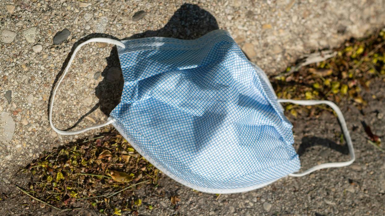 A discarded face covering lies on the ground