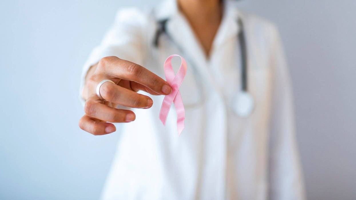 A doctor holding a breast cancer ribbon.