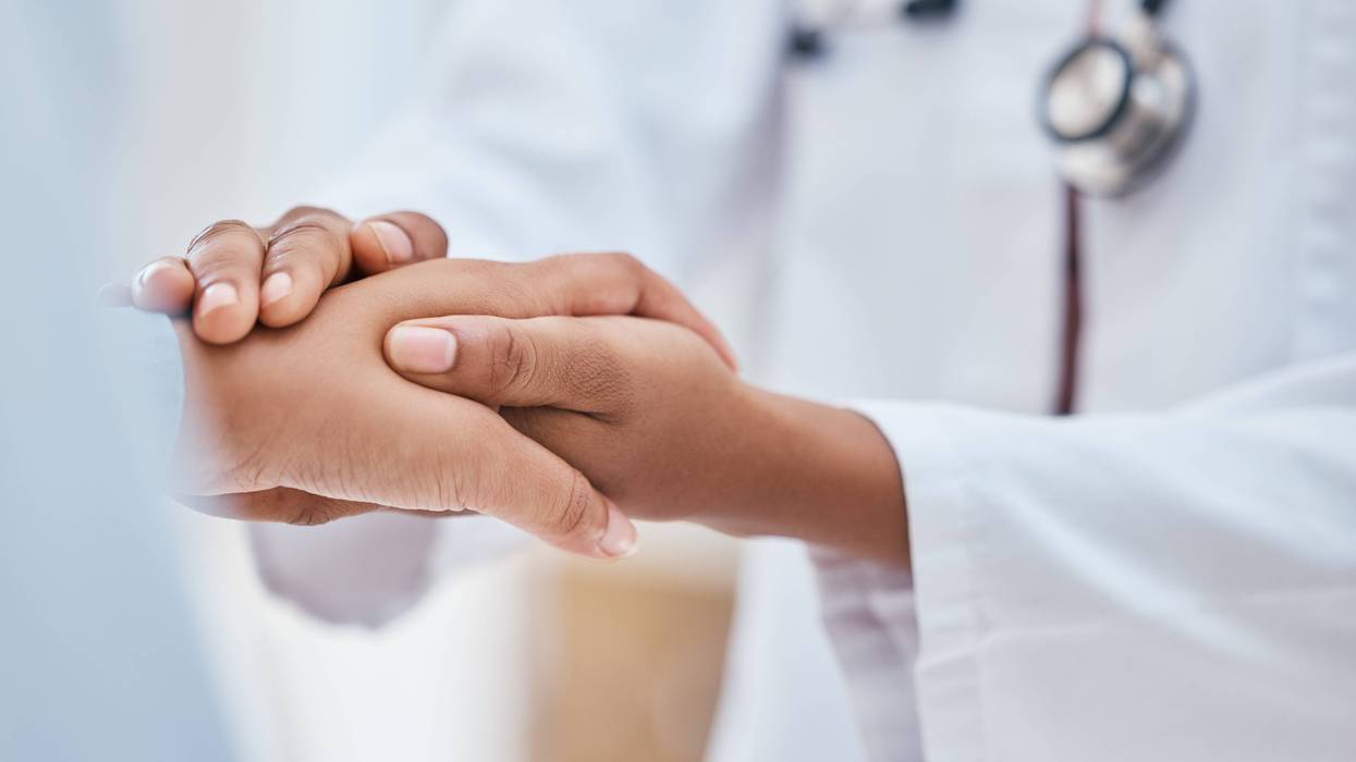 A doctor holds a patient's hand.