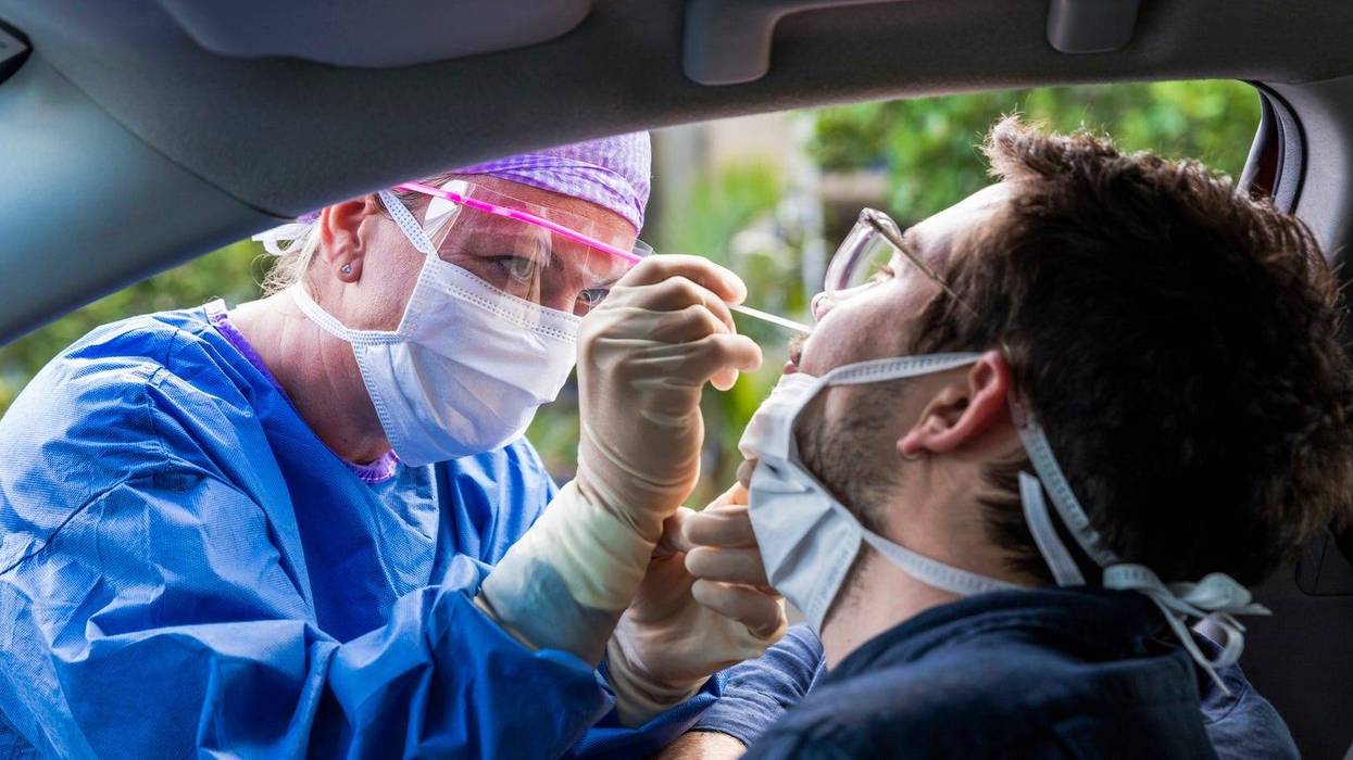 A doctor in a protective suit taking a nasal swab from a person to test for possible coronavirus infection