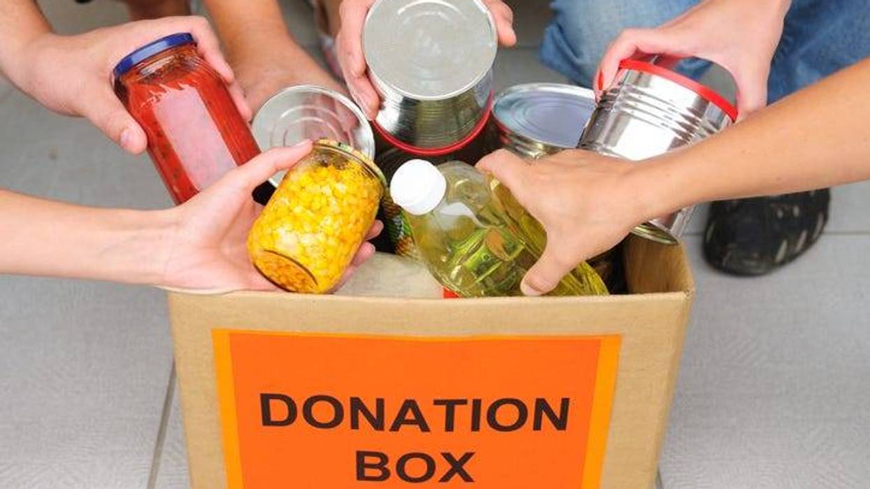 A donation box being filled with canned food and non-perishables by volunteers