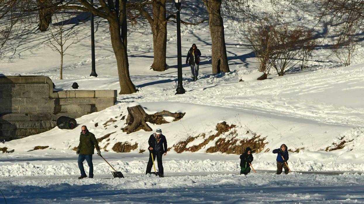 A family is seen shoveling snow to reveal the ice on the Washington Park Lake in Albany, N.Y