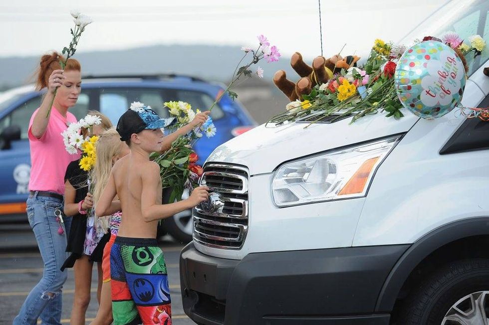A family places flowers on vehicles of the victims of the Ride The Ducks accident on July 20, 2018 in Branson, Missouri.