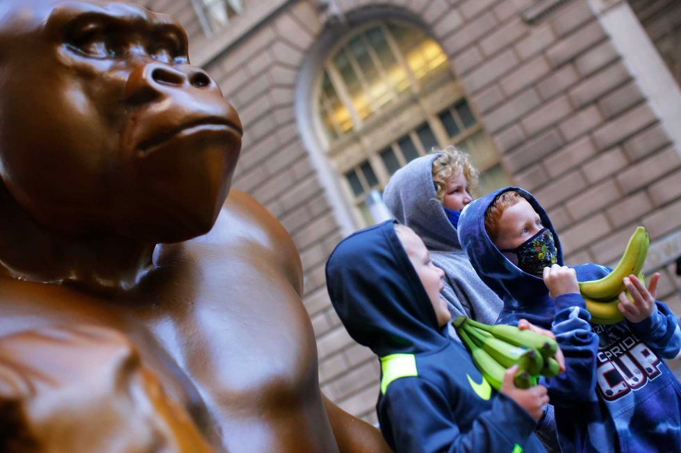 A family visiting NYC from Indianapolis takes a photo with a Harambe statue installed in front of the Charging Bull statue on October 18, 2021 in New York City