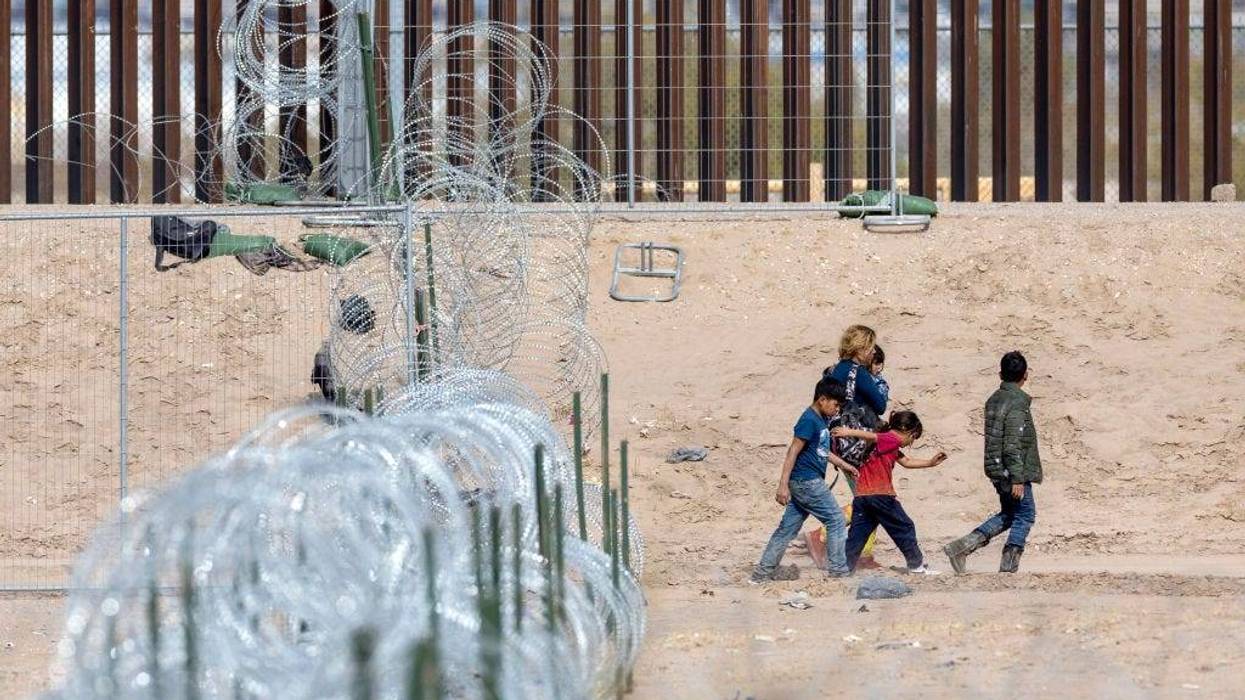 A family walks past coils of razor wire after crossing the Rio Grande into El Paso, Texas on January 30, 2024 from Ciudad Juarez, Mexico. Migrants who managed to get through the wire on the bank of the Rio Grande were then sent on to nearby U.S. Border Patrol agents for further processing.
