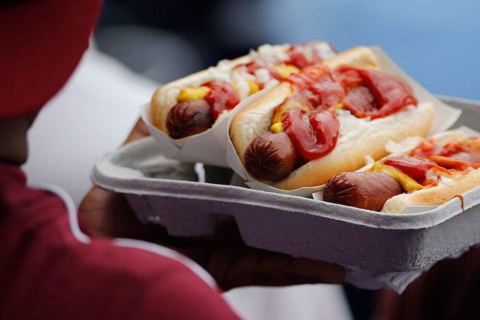 A fan takes his seat with a tray of hot dogs.