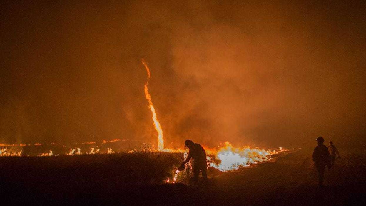 A fire whirl, also called a fire devil, forms as firefighters use drip torches to set a backfire at night in an effort to make progress against the Thomas Fire before the winds return with the daylight near Lake Casitas on December 9, 2017 near Ojai, California. Strong Santa Ana winds have been feeding major wildfires all week, destroying hundreds of houses and forcing tens of thousands of people to stay away from their homes. (Photo by David McNew/Getty Images)