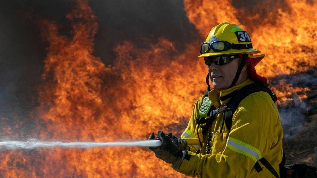 A firefighter protects a home from getting too hot as a backfire is set to protect homes and try to contain the Blue Ridge Fire on October 27, 2020 in Chino Hills, California.