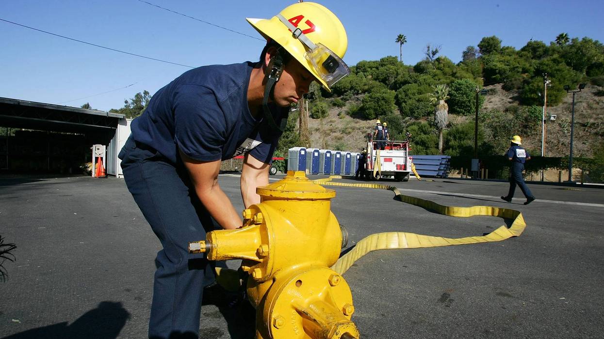 A firefighter recruit practices rapdily dismantling a hose-lay during training.