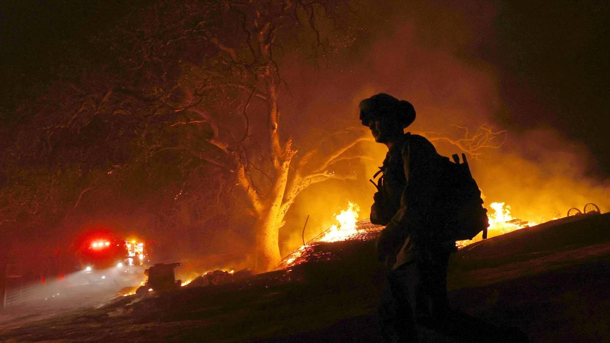 A firefighter walks by a burning wood pile while battling the Glass Fire on October 01, 2020 in Calistoga, California