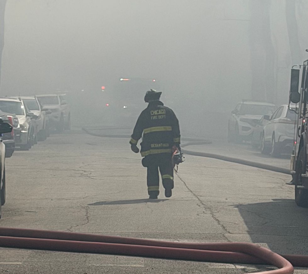 A firefighter walks down Fulton Avenue as crews work to extinguish a fire that destroyed three houses on the city's West side.