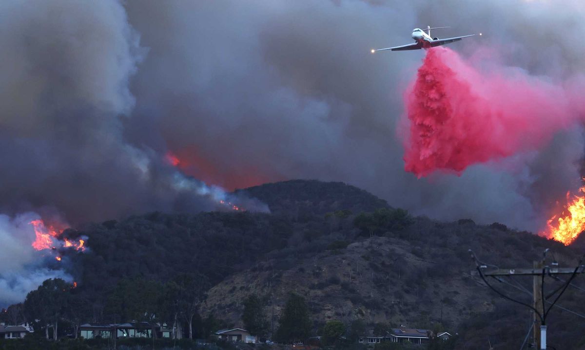 A firefighting aircraft drops the fire retardant Phos-Chek as the Palisades Fire burns amid a powerful windstorm on January 7, 2025 in Pacific Palisades, California.