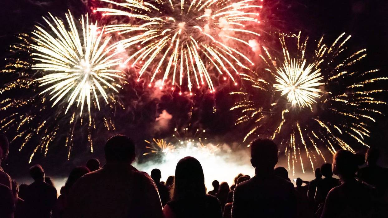 A fireworks display with people in foreground watching