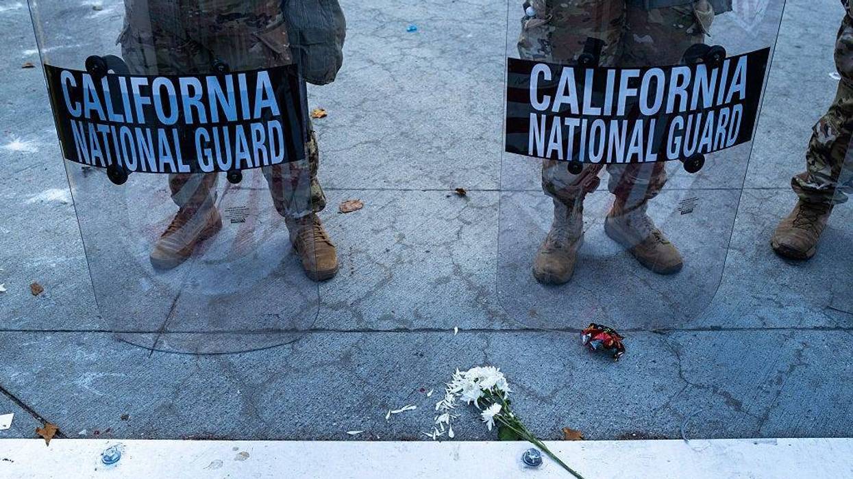 A flower is placed in front of members of the National Guard as they confront protesters in downtown Los Angeles as demonstrations continue after a series of immigration raids began last Friday on June 13, 2025, in Los Angeles, California