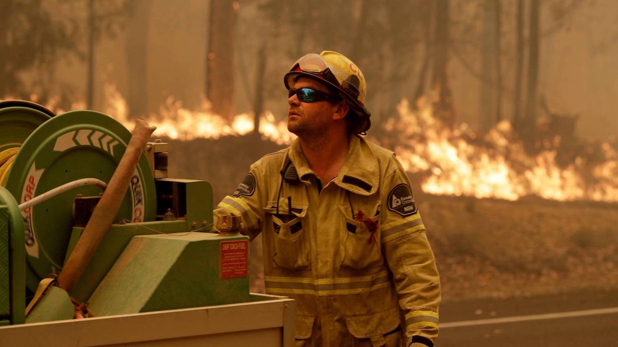 A Forest Corporation worker manages a fire hose as he battles a fire near Moruya, Australia, Saturday.