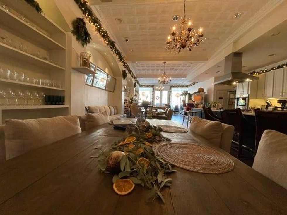 A giant open kitchen overlooks cozy wooden tables and tan, puffy pillows underneath soft lit chandeliers. There is retail from local artists and cheeses and charcuterie from Illinois growers in front.