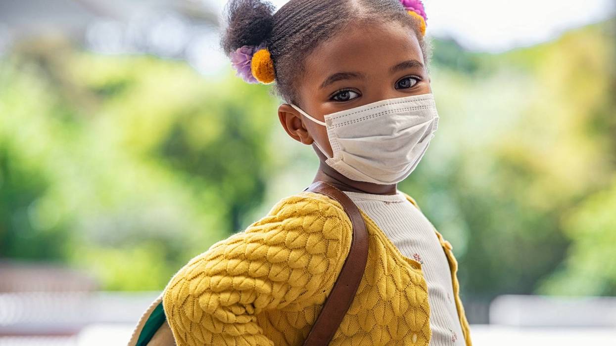 A girl about to attend school, wearing a face mask