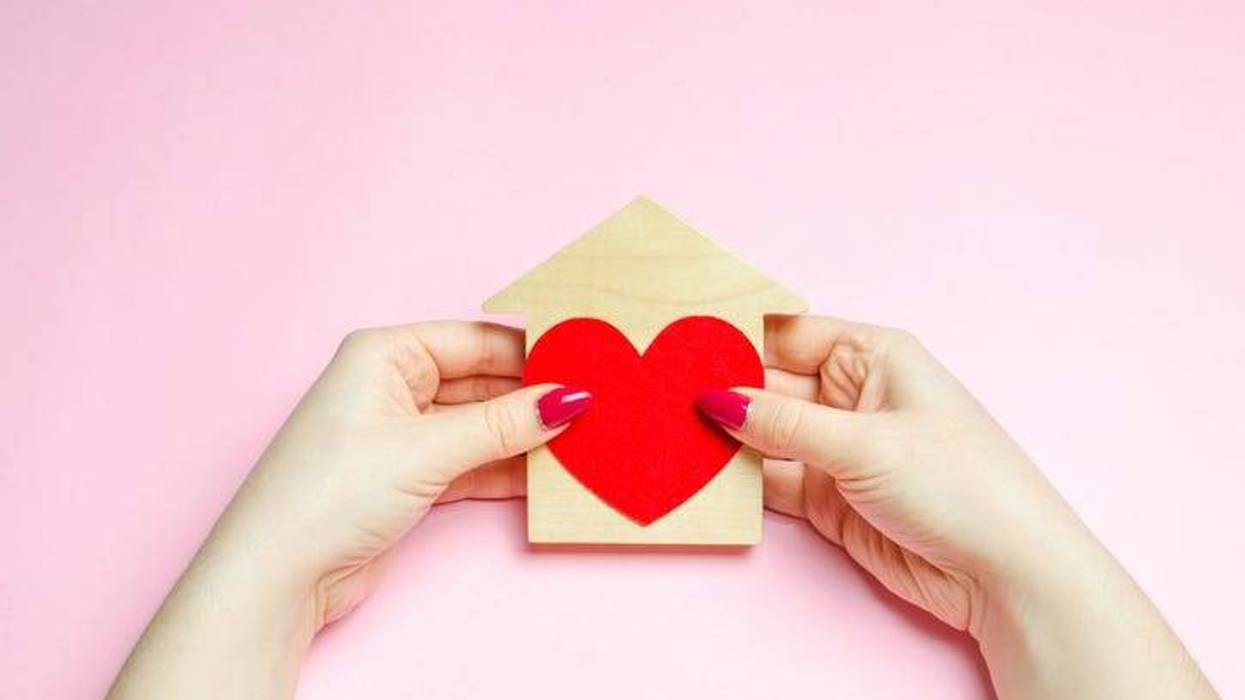 A girl holds a house and heart in her hands.