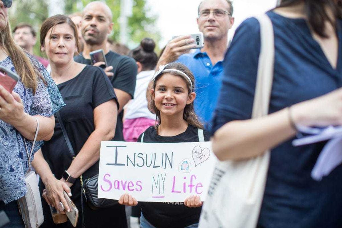 A girl holds a sign that reads "Insulin Saves My Life" while Democratic presidential candidate, U.S. Sen. Bernie Sanders (D-VT) talks about the cost of insulin in the USA versus Canada as he joins a group of people with diabetes on a trip to Canada for affordable Insulin on July 28, 2019 in Windsor, Canada.