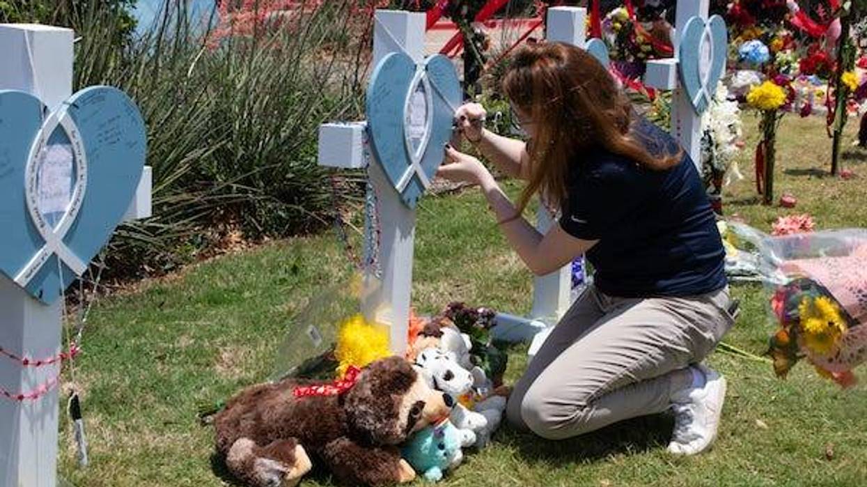 A girl writes on a memory board to mourn victims of a mass shooting in front of an outlet mall in Allen, Texas, the United States, on May 8, 2023