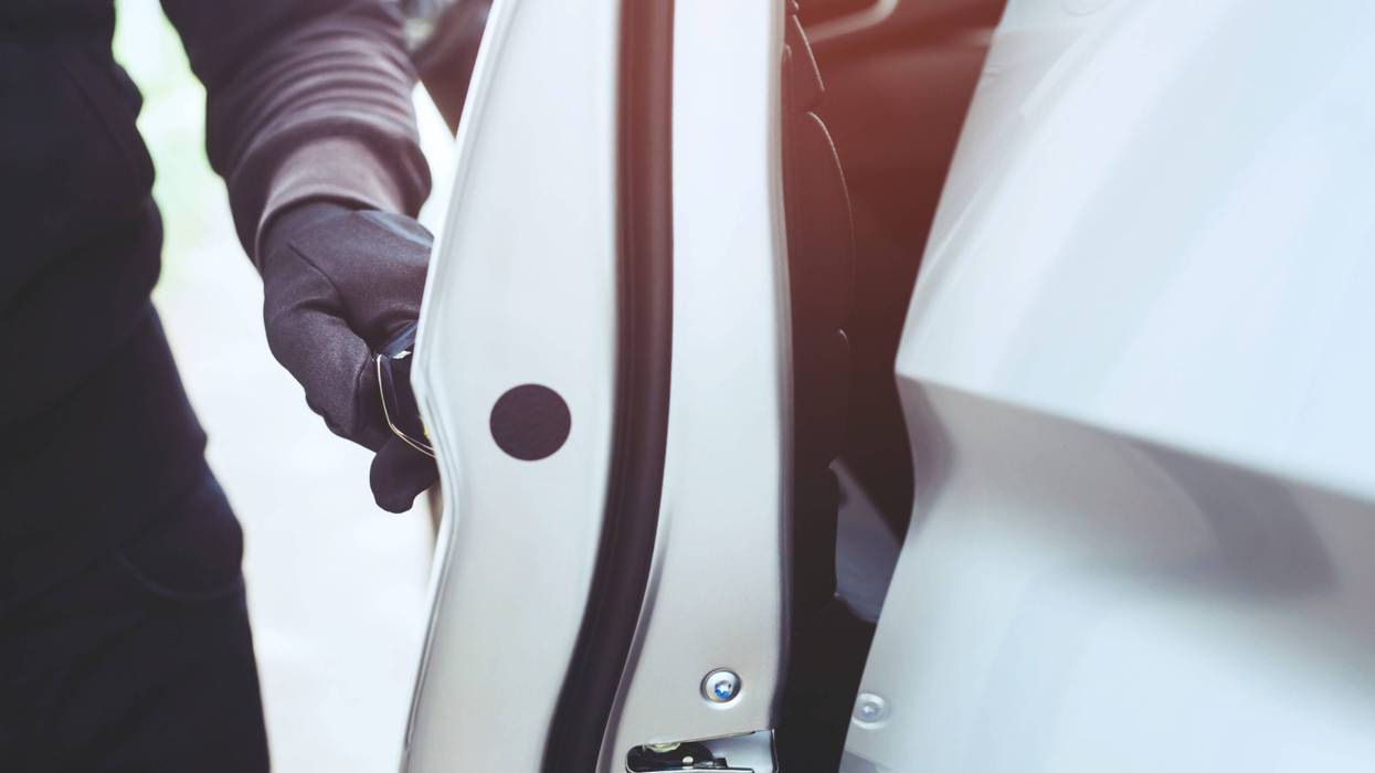 A gloved hand opens a car door.