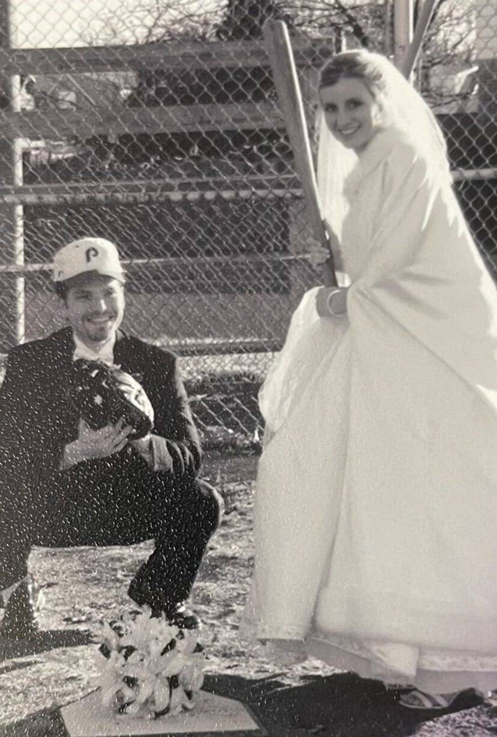 A groom and bride on home plate playing baseball.