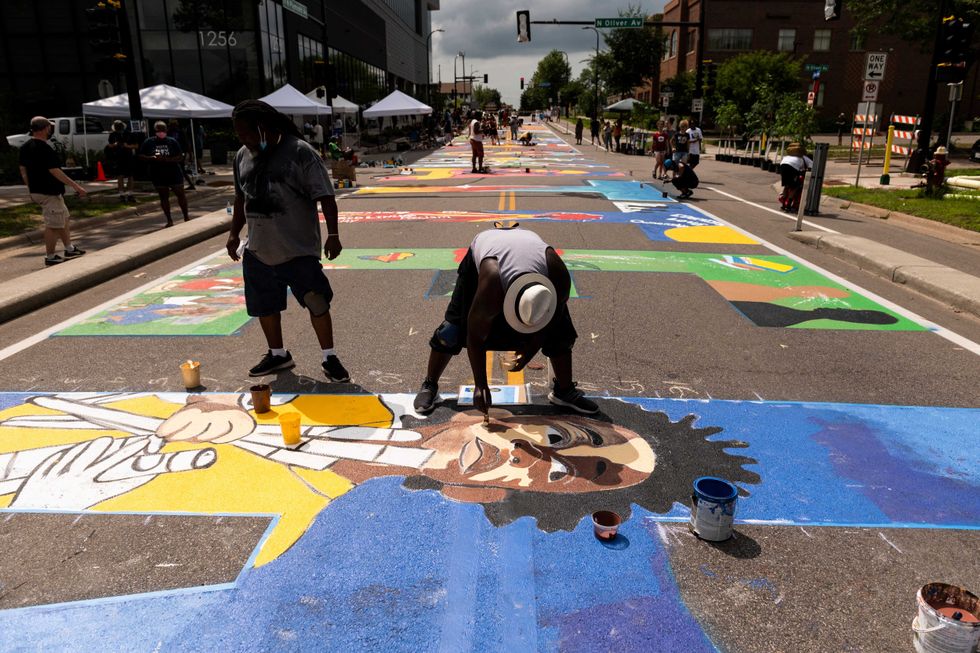 A group of artists and volunteers paint a Black Lives Matter mural on the street outside the Minnesota African American Heritage Museum and Gallery on July 18, 2020 in Minneapolis, Minnesota.