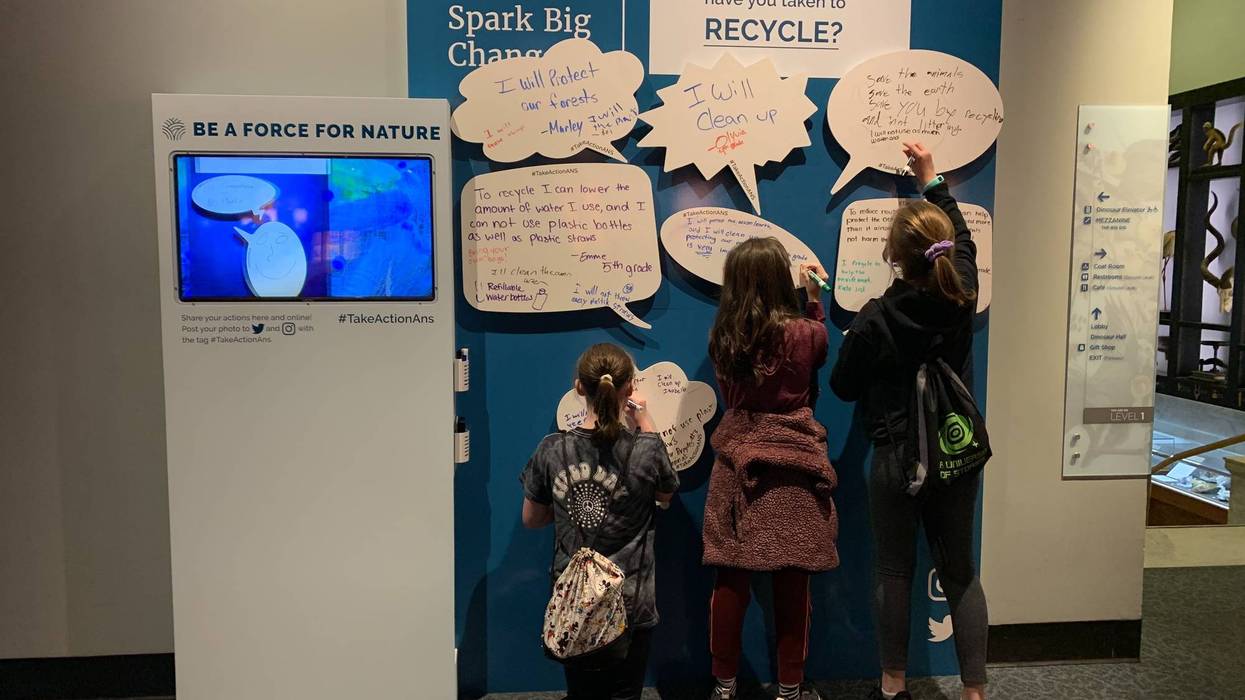 A group of kids write down what they changes they plan to make to positively affect the environment at the Academy of Natural Sciences.