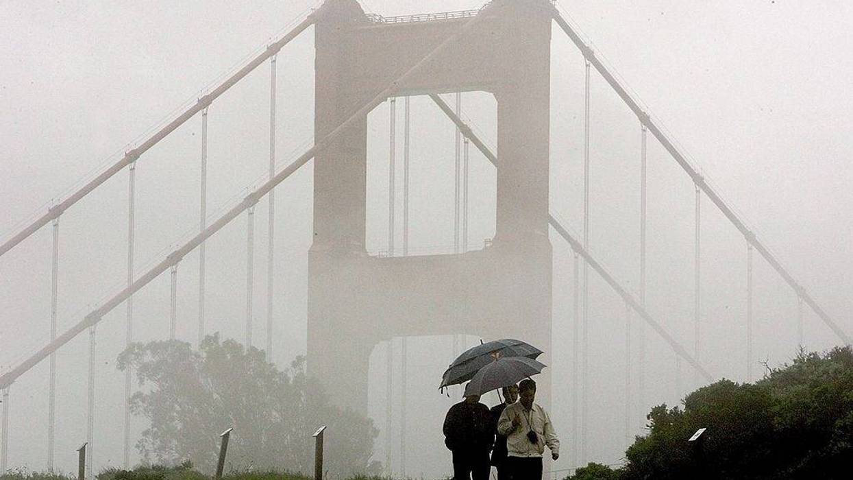 A group of men walk through the rain near the north tower of the Golden Gate Bridge April 12, 2006 in Sausalito, California.