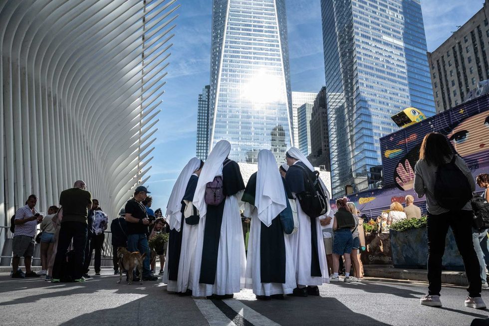 A group of nuns pray outside of the perimeter of the 9/11 memorial site during a moment of silence on September 11, 2024 in New York City