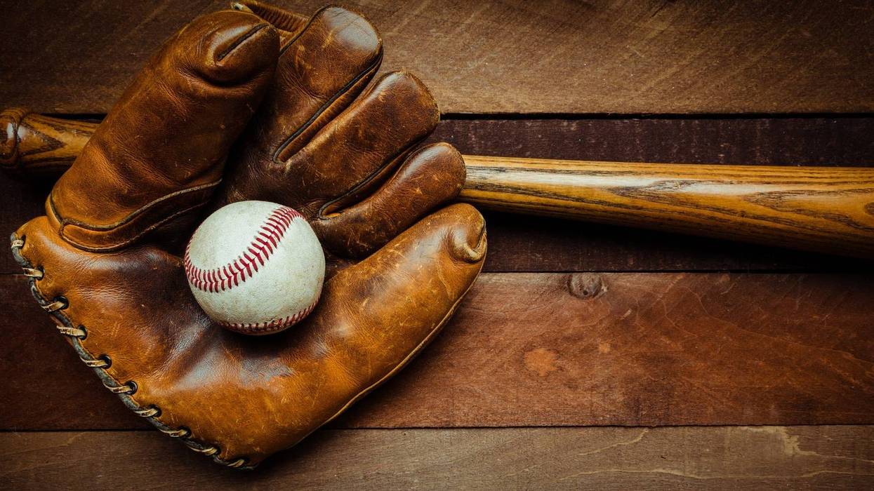 A group of vintage baseball equipment, bats, gloves, baseballs on wooden background