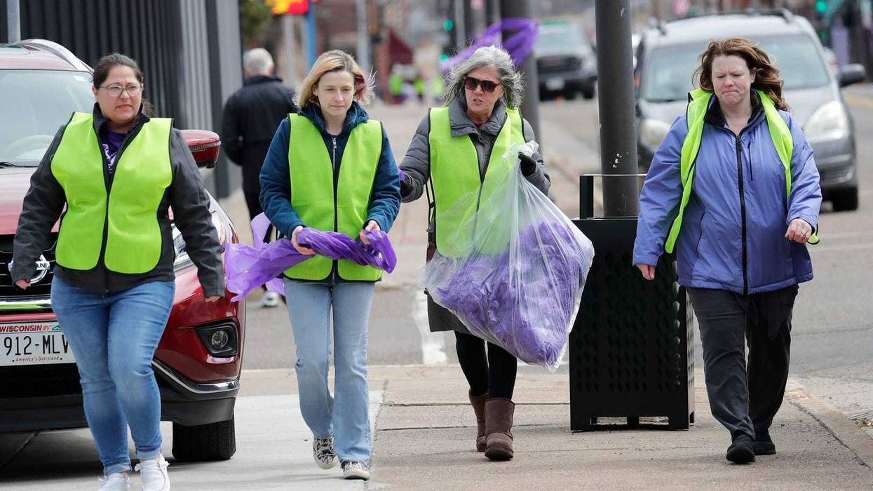 A group of women hang purple ribbons in downtown Chippewa Falls, Wisconsin as officials investigated the homicide of Lily Peters, 10, Tuesday, April 26, 2022.