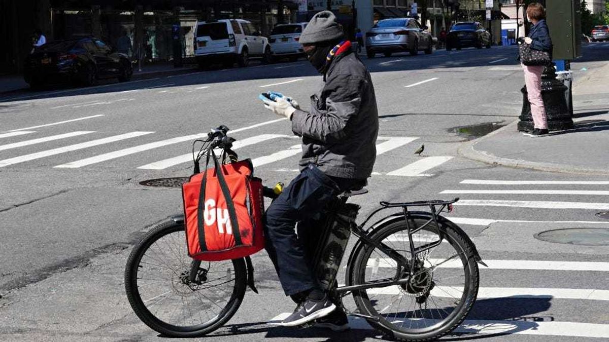 A Grubhub delivery person checks his phone during the coronavirus pandemic on May 3, 2020 in New York City.
