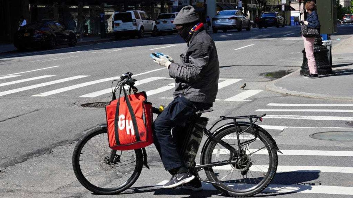 A Grubhub delivery person checks his phone during the coronavirus pandemic on May 3, 2020 in New York City.