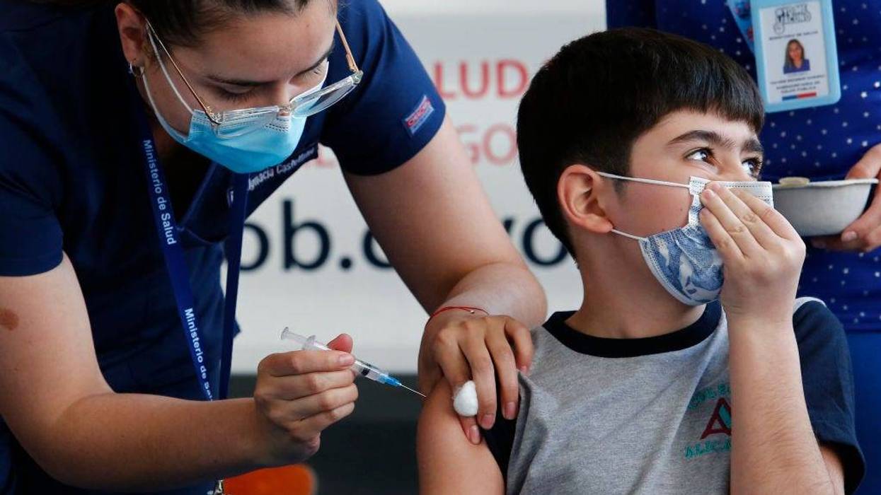 A health worker administers the first dose of Sinovac vaccine to a student as part of the immunization plan against COVID-10 for children aged 6 to 11 at Alicante del Rosal school on October 1, 2021 in Santiago, Chile.