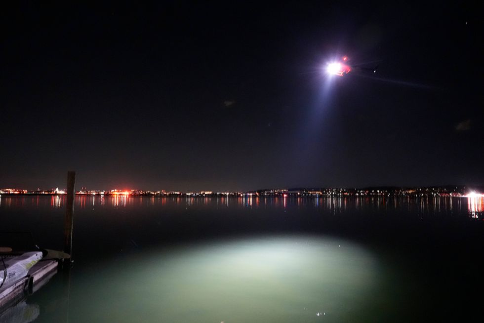 A helicopter uses a spotlight on the Potomac River near Ronald Reagan Washington National Airport, Jan. 30, 2025, in Arlington, Va.