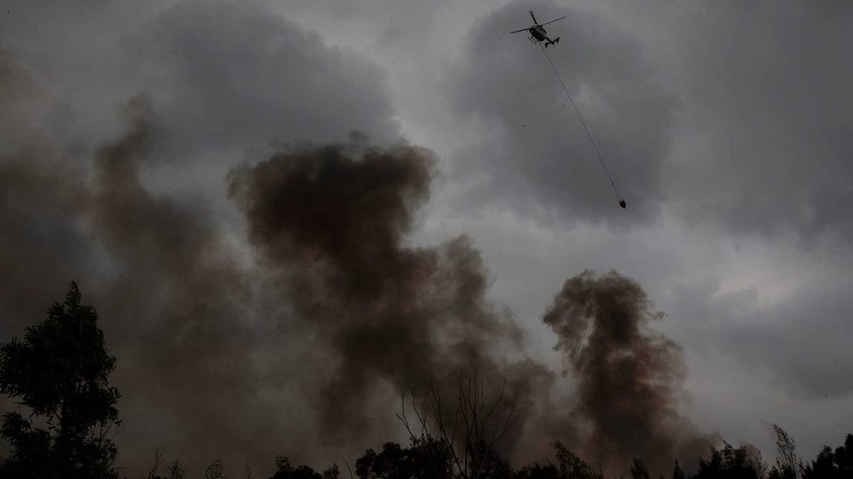 : A helicpter water bombs a fire at Voyager Point in western Sydney on January 05, 2020 in Sydney, Australia.