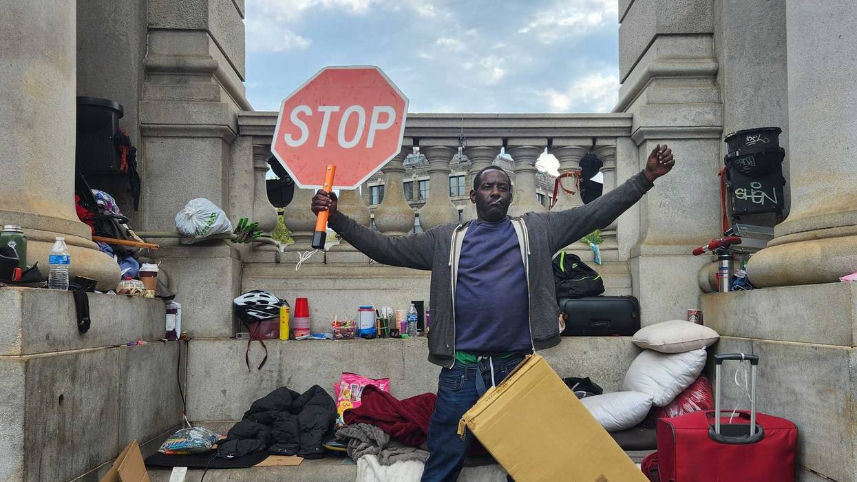 A homeless man defiantly raises a stop sign after police and sanitation workers force him to dismantle his makeshift tarp shelter at the base of the Manhattan bridge.
