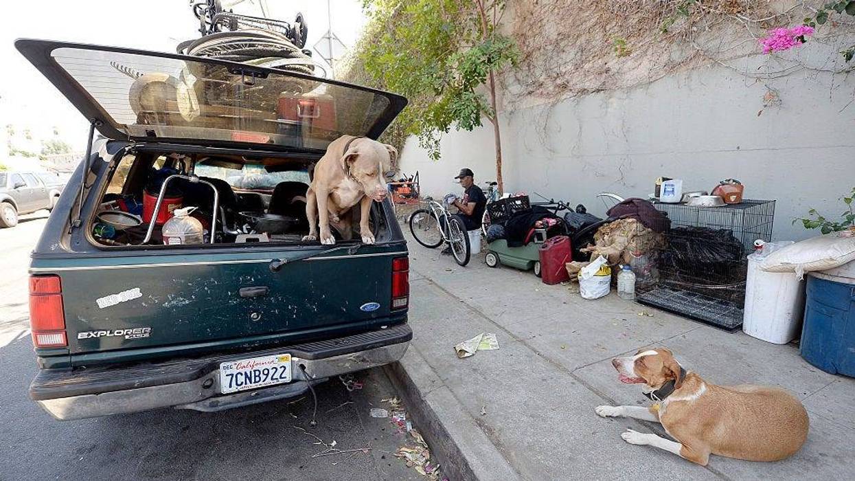A homeless man for over 30 years who lives inside his car repairs a bicycle as his dog Honey and neighbor's dog Niko stand guard Sept. 23, 2015, in the Hollywood section of Los Angeles, California. Los Angeles County's Blue Ribbon Commission on Homelessness is holding its first meeting Wednesday.