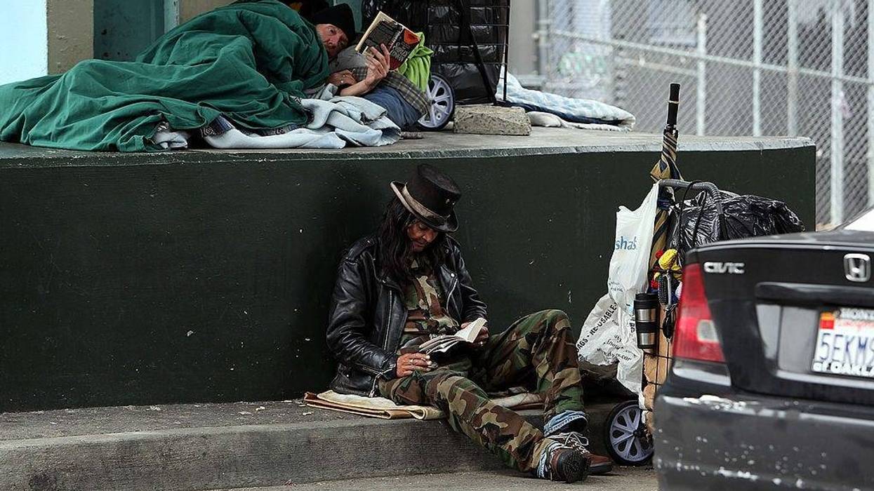 A homeless man named Joe (R) reads a book under an overpass where he sleeps with a friend January 25, 2010 in San Francisco, California.