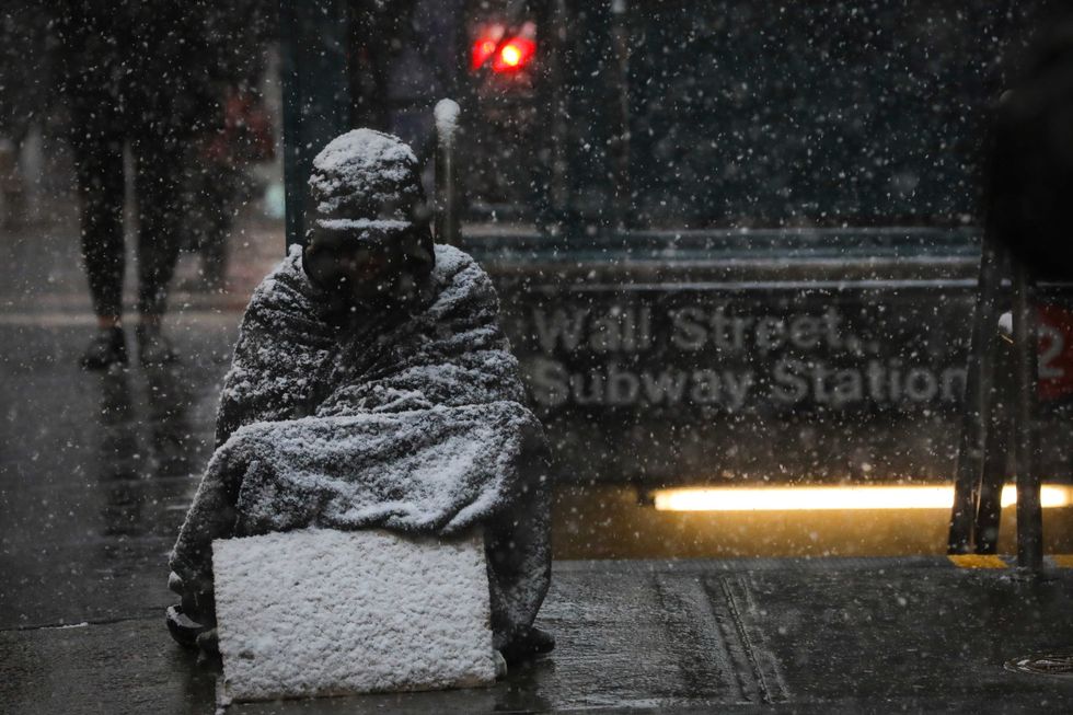 A homeless man sits in the falling snow in the Financial District, January 30, 2019 in New York City.