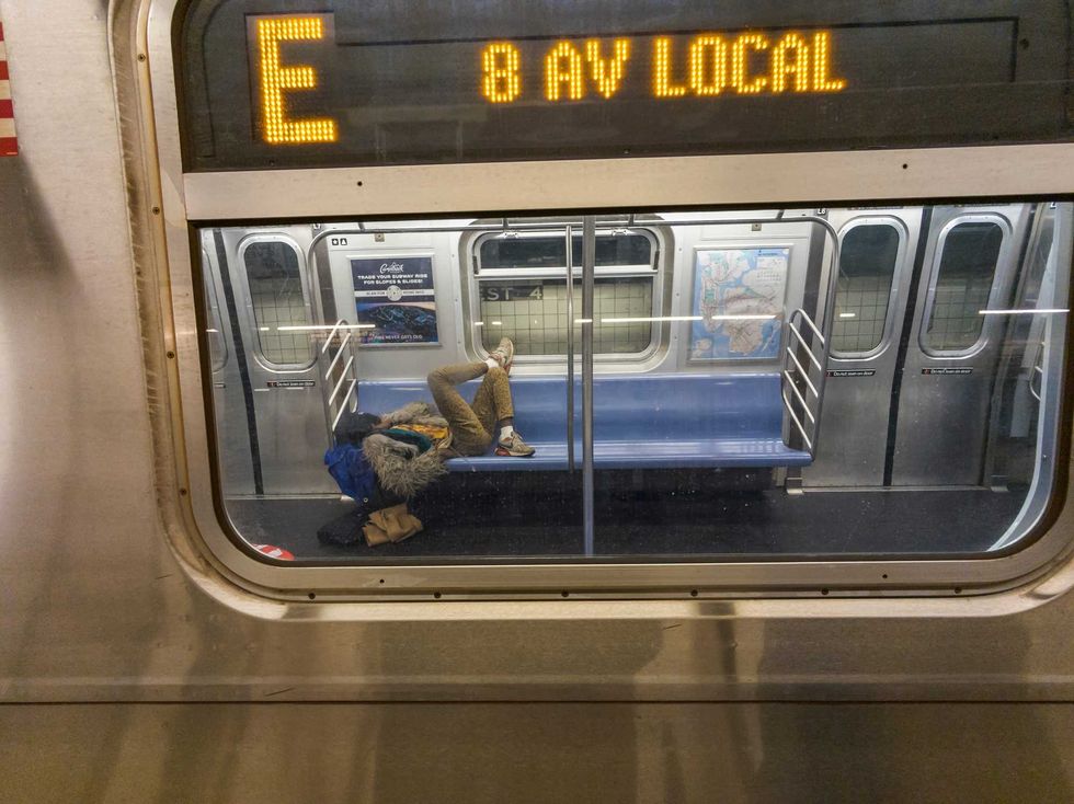 A homeless man sleeps on an E train on March 2, 2024