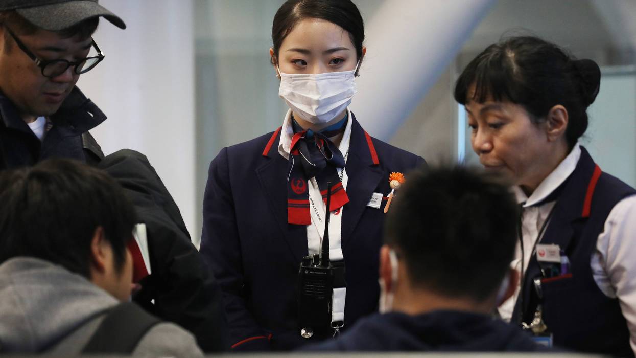A Japan Airlines worker (C) wears a face mask while working inside a terminal at Los Angeles International Airport on Jan. 23, 2020.