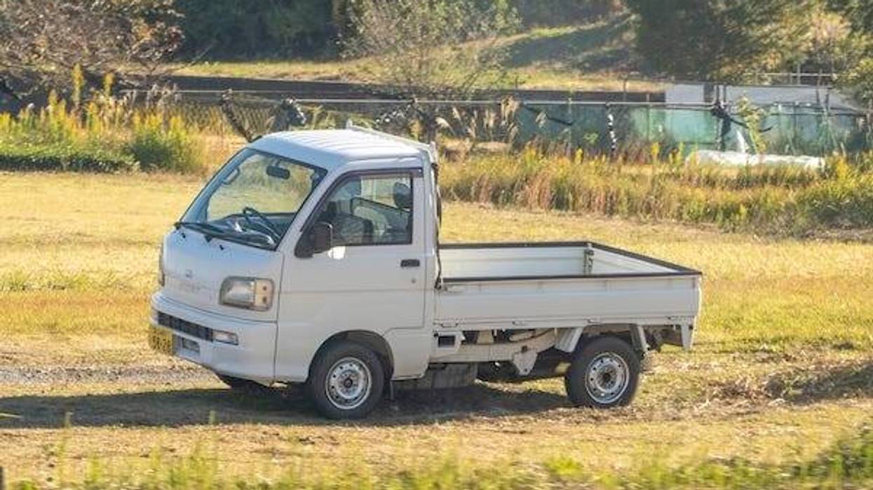 A Japanese mini truck (Kei truck) driving in the grass