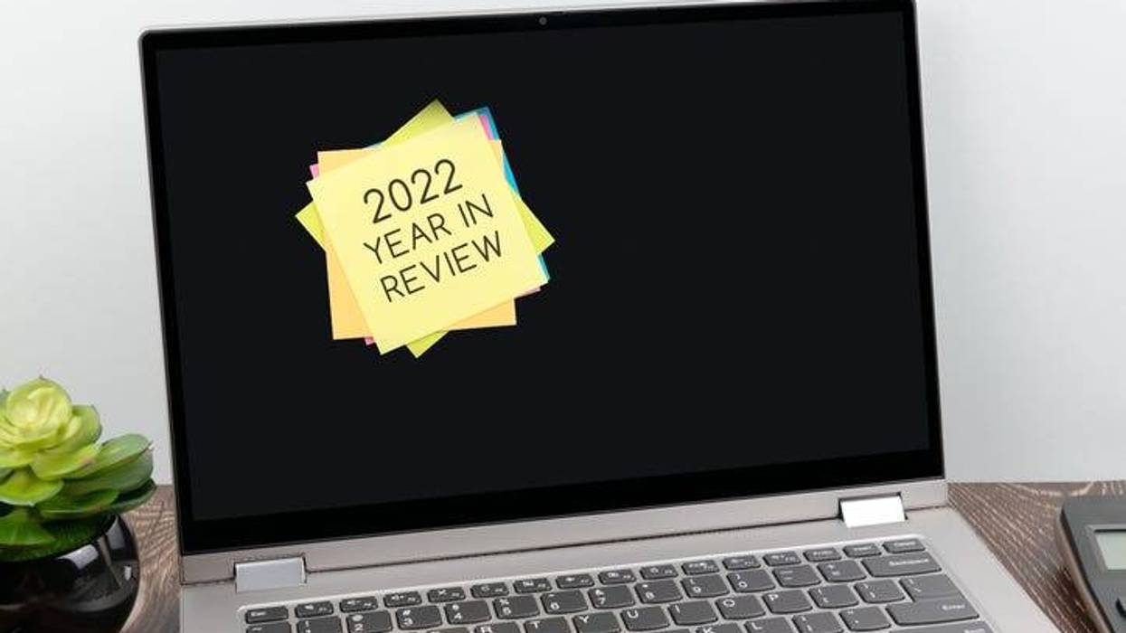 A laptop is open with a stack of multi-colored post-its stuck to the screen. The post-it on top reads "2022 Year in Review"