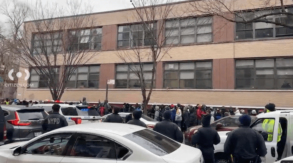 A large crowd of migrants wait outside an intake center in the East Village on Saturday; the NYPD is also on the scene.