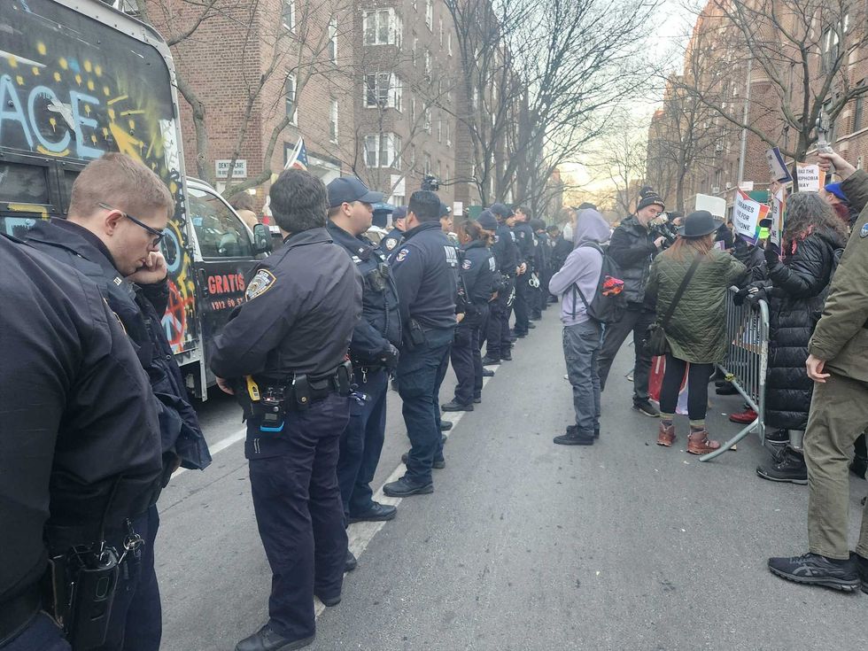 A line of police stands in the street between the anti-LGBTQ protesters on the left and the Drag Story Hour supporters on the right.