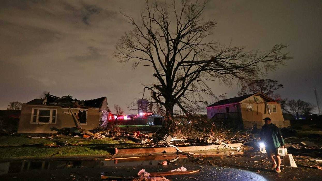 A man carries jugs of water past heavily damaged houses in Arabi, Louisiana after an apparent tornado touched down on Tuesday evening, March 22, 2022.