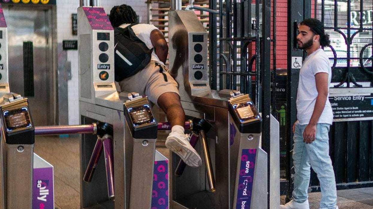 A man goes over a subway turnstile without paying the MTA fare as other wait for him to open the door at a subway station in middle Manhattan on June 5, 2023